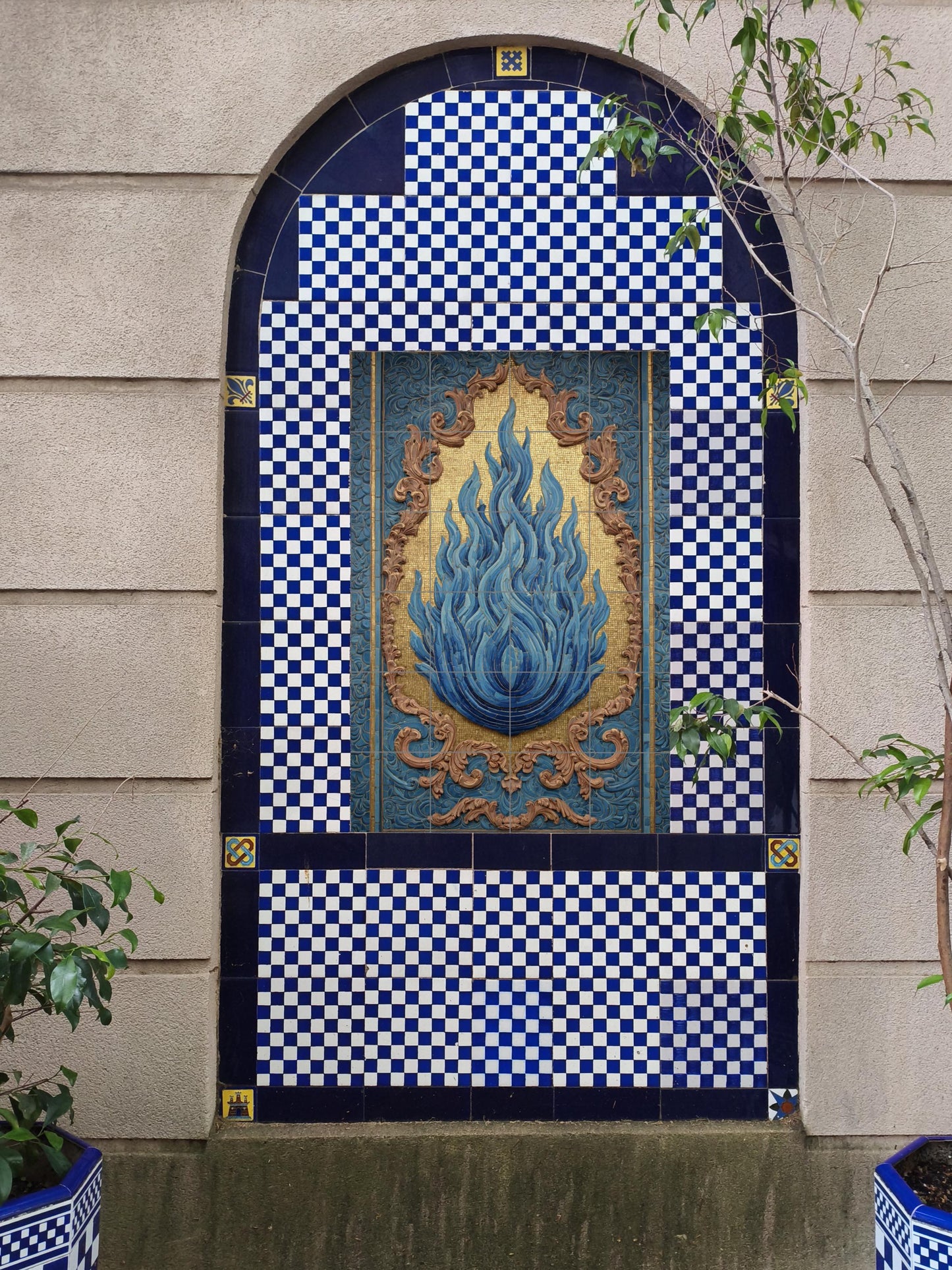 Blue flame on golden mosaic: impressive ceramic mural of Sacred Fire with ornamental relief and profound symbolic elegance.