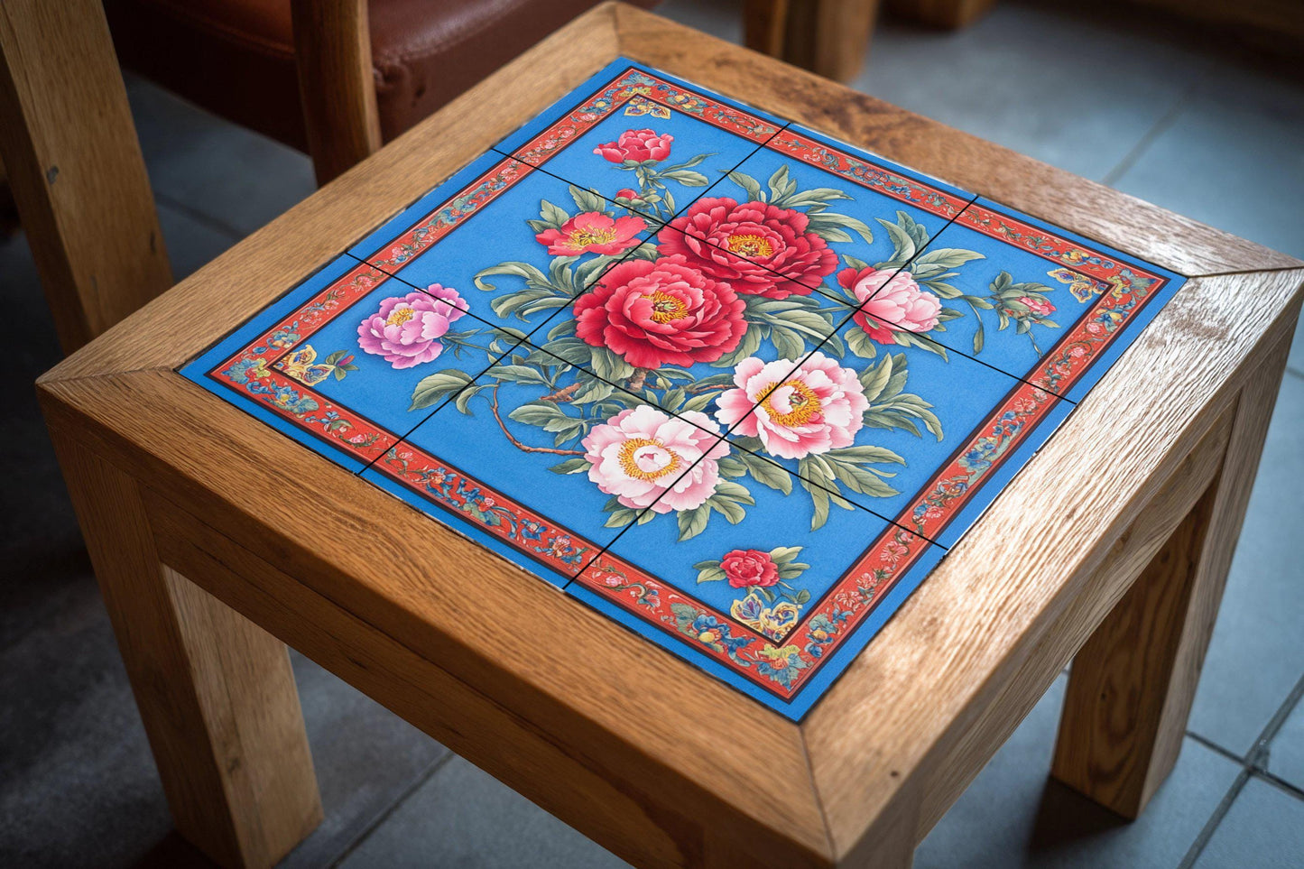 Large ceramic floral mural: intense red and pink flowers on a deep blue with an ornate border, striking tile wall art for impactful interiors.