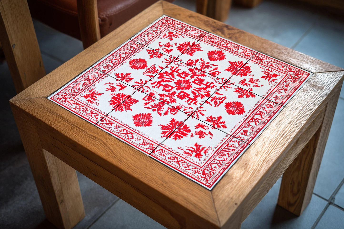 Ceramic mural: design inspired by red geometric embroidery, traditional urban motifs with ornamental borders on white tiles.