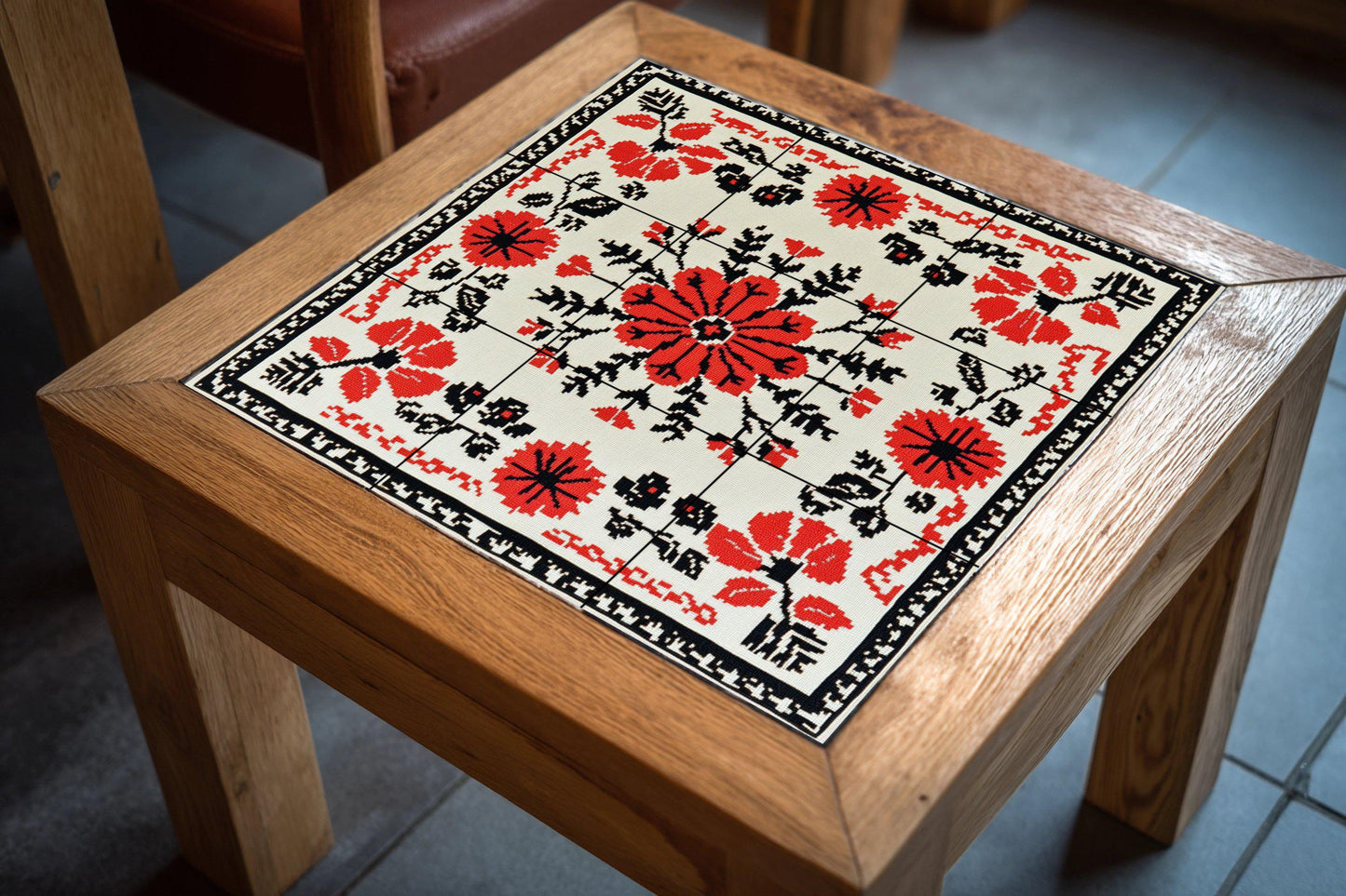 Romanian embroidered mural: floral ceramic mural art in red and black cross stitch with folk vine stitch border, Balkan textile design.