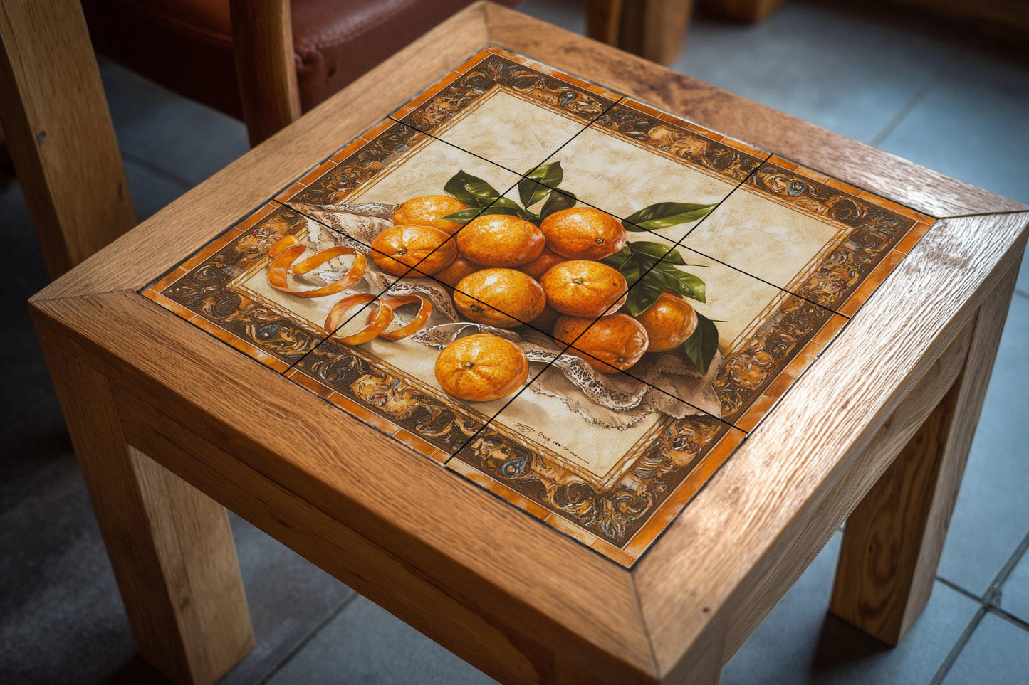 Ceramic tile mural with oranges, curled peels, lace fabric and decorative wall art panel with fruit still life and ornate baroque border.