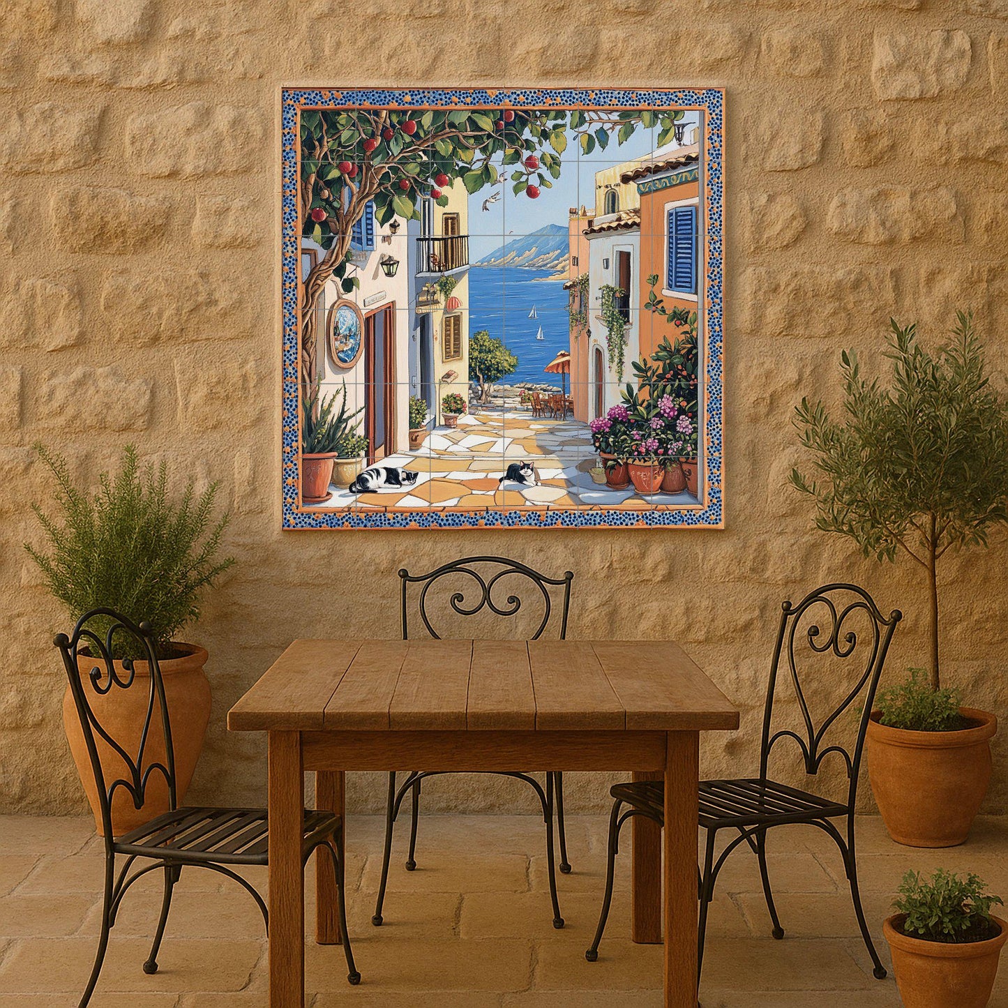 Ceramic tile mural with street scene of a coastal town, fruit tree, flower pots, houses by the sea and black and white cats resting on the pavement.